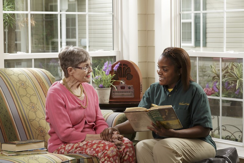 Caregiver reading book to senior