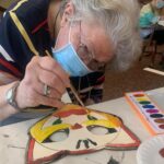Old woman painting a cut mask
